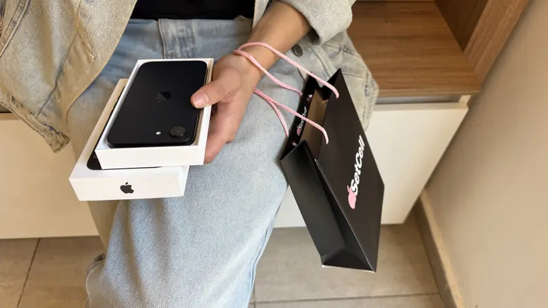 Clienta sosteniendo un iPhone en su caja junto a una bolsa de SetCell