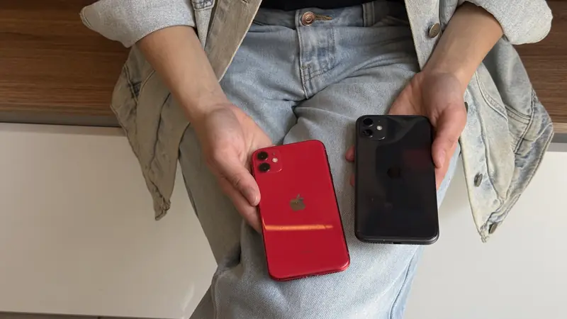 Clienta con dos iPhone 11, uno rojo y uno negro, en las manos